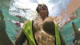 August Ames frolics in a swimming pool with her huge curves
